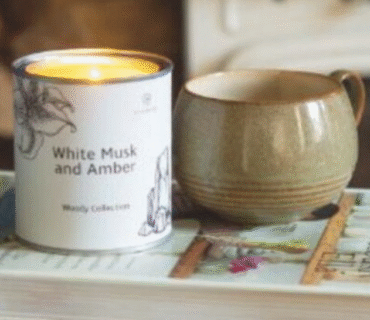 Image of a lit scented candle on a book promoting wellbeing