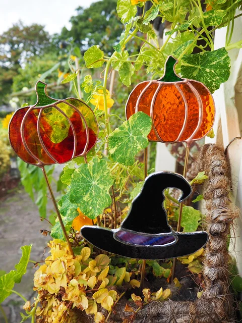 Image of stained glass plant stakes shaped like Pumpkins and a Witches Hat.